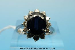An 18ct white gold ring set with an oval sapphire surrounded by diamonds (size L)