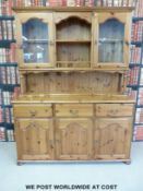 A modern pine dresser, the top section having central shelves flanked by glazed cupboards,