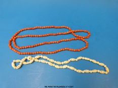 A coral necklace of spherical beads together with a bone necklace and earrings