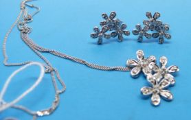 A 9ct white gold pendant set with diamonds in a floral design and matching earrings