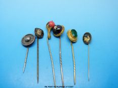 A group of yellow metal stick pins variously set with an oval green stone, a garnet and a pearl,