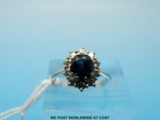 An white metal ring marked 18ct set with a sapphire to the centre surrounded by diamonds (size I/J)