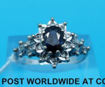 A white metal ring set with an oval sapphire surrounded by diamonds (size Q)