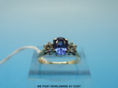 An 18ct gold ring set with an oval tanzanite flanked by diamonds (size L)