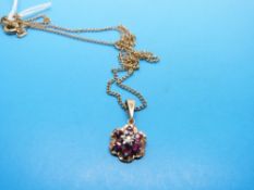 A 9ct gold pendant set with rubies and a diamond in a cluster on a 9ct gold chain