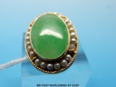 A 14ct gold ring set with an oval cabochon of jadeite surrounded by pearls (size H)