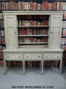 A pine dresser, the top with plate and cup racks flanked by cupboards,