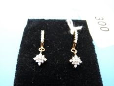 A pair of 9ct gold earrings set with diamonds in a drop cluster