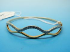 A 9ct gold bangle set with diamonds in a wave design