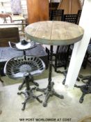 A rustic table with cast iron base together with two similar style cast iron bar stools (height