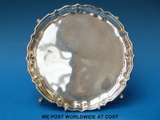 A George V hallmarked silver salver with shaped edge, raised on four hoof feet, Ldn 1915,