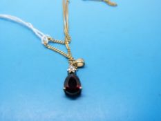 A 9ct gold pendant set with garnet and diamonds on a 9ct gold chain