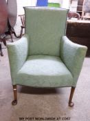 An upholstered armchair with sweeping arms raised on cabriole legs