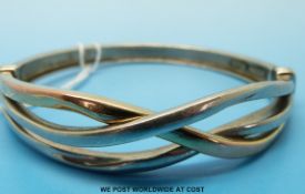 A silver and 9ct gold bangle with intertwined design