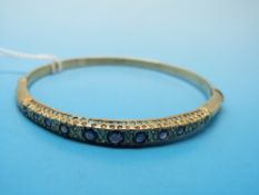 A 9ct gold bangle set with sapphires and diamonds