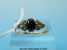 A 9ct gold ring set with an oval sapphire flanked by three clear stones to each side (size M)
