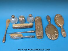 An Art Nouveau white metal-backed dressing table set comprising hand mirror, four various brushes,