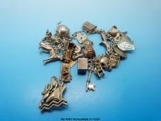A silver charm bracelet with charms including a dog and hinged charms together with a white metal