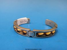 A silver bangle set with sections of snake skin