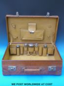 A leather suitcase with hallmarked silver and cut glass dressing table bottles fitted to interior