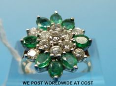 A 9ct gold ring set with oval emeralds and round cut diamonds in a cluster (size N)