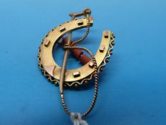 A gold horseshoe and whip brooch
