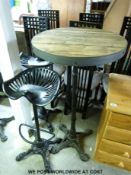 A rustic table with cast iron base together with two similar style cast iron bar stools,