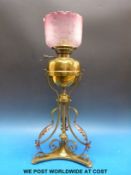 A 19thC ornate brass oil lamp in the manner of Benson with etched cranberry glass shade (height