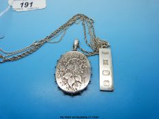 A hallmarked silver locket with floral decoration and a silver ingot.
