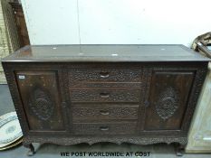 A brass inlaid and carved Northern Indian sideboard with four straight drawers flanked by cupboards