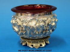 A possibly Chinese, Indian or Burmese embossed white metal salt with cranberry glass liner,