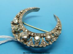A Victorian gold and platinum brooch set with old cut diamonds in a crescent shape the largest