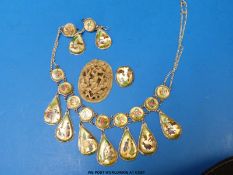 A white metal necklace set with decorative panels,
