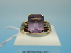 A yellow metal ring set with an emerald cut amethyst and diamonds (size S)