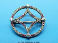 A gold circular brooch set with alternating rubies and diamonds