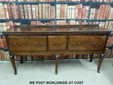 A Georgian oak three drawer sideboard / dresser base raised on cabriole legs and with a shaped