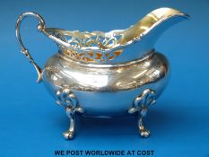 A George V hallmarked silver cream jug with gilt wash interior raised on four paw feet,