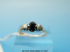 An 18ct gold ring set with an oval cut sapphire flanked by two diamonds (size N/O)