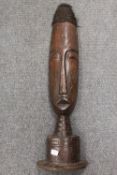 An African wooden carving depicting a mask on stand, hight 77 cm. CONDITION REPORT: Good time aged