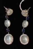 A pair of moonstone earrings, set with diamonds and sapphires, each mounted in white gold. (2)