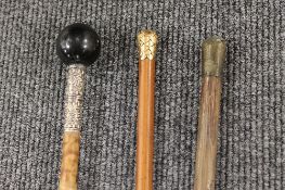 A nineteenth century lady's cane, with yellow metal mount, together with two other sticks