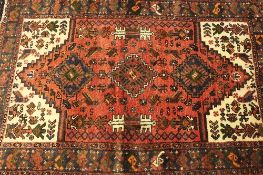 An Iranian wool rug, on red ground, 138 cm x 94 cm.