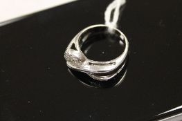 A diamond cross-over ring in white metal. CONDITION REPORT: Tested as white gold, good condition.