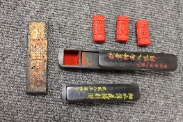 Two Chinese lacquered desk pots, each containing seals, together with a wooden printing block and