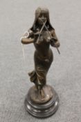 A bronze study depicting a Lady playing a flute on black marble socle, height 42 cm.  CONDITION