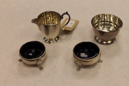 A silver cream jug and sugar bowl, together with a pair of silver salts with glass liners. (4)