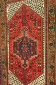 An Iranian wool rug, on red ground, 149 cm x 97 cm.