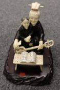 An early twentieth century carved ivory and Chinese hard wood figure of a musician with pupil,