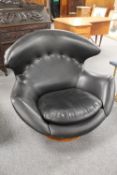 A late twentieth century contemporary shell shaped swivel lounger chair upholstered in black vinyl,