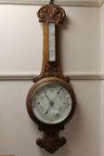 A late Victorian carved oak aneroid barometer.
